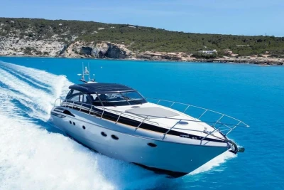 2005 Princess V58 yacht cruising in clear blue waters near rocky coastline.