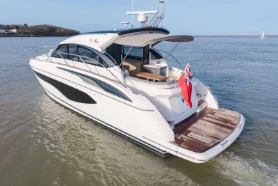 Luxurious 2018 Princess V50 yacht cruising on calm waters with a red flag displayed.