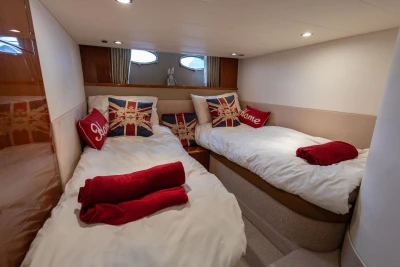Luxurious 2006 Princess V48 yacht cabin with twin beds, Union Jack pillows, and red accents.