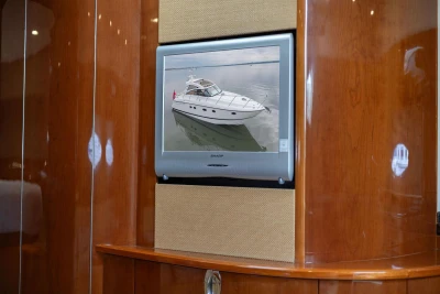 Wall-mounted TV displaying a 2006 Princess V48 yacht, surrounded by polished wooden paneling.