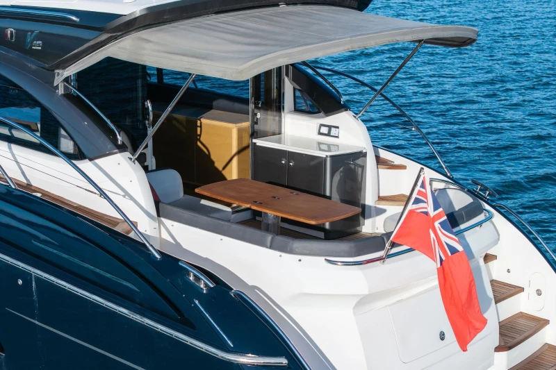 2014 Princess V48 yacht with flag, featuring outdoor seating and sleek design on blue water.