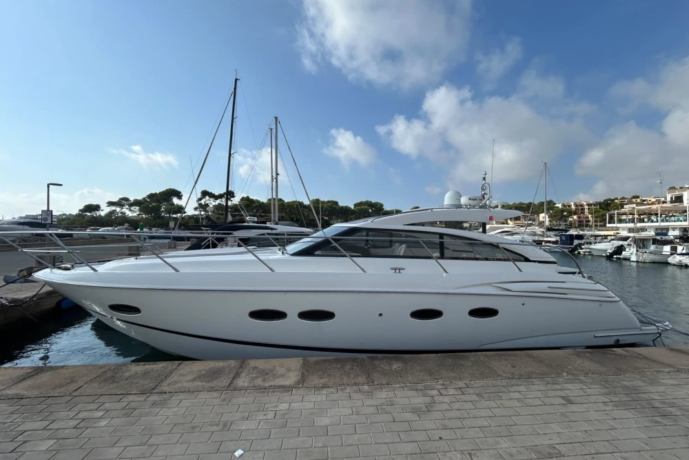 Luxury 2012 Princess V42 yacht docked in a marina under a clear blue sky.
