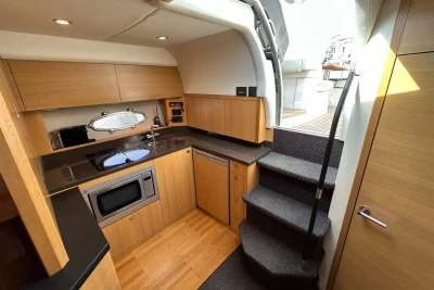 Modern kitchen interior on a 2012 Princess V42 yacht, featuring wood cabinetry and sleek appliances.