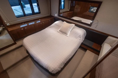 Luxurious bedroom interior of 2012 Princess V52 yacht with elegant bedding and wood accents.