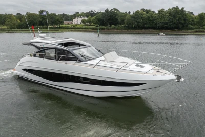 2023 Princess V50 yacht cruising on a serene river with lush greenery in the background.