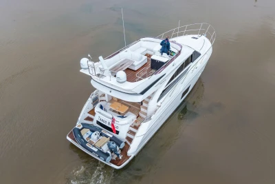 Luxury 2017 Princess 52 yacht cruising on calm waters, aerial view.