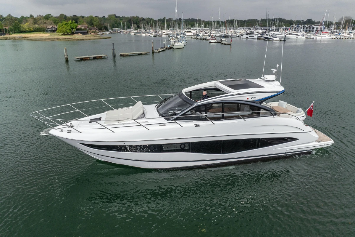 2025 Princess V50 yacht on calm water, surrounded by marina and boats.