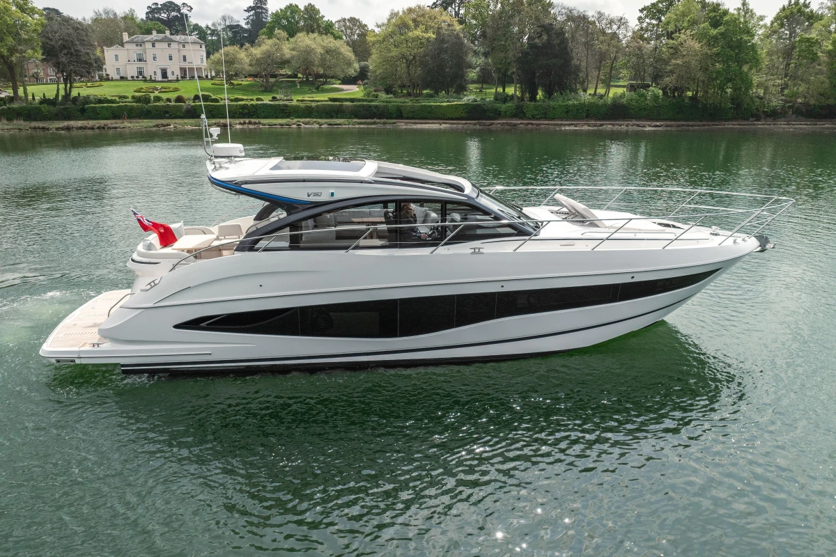 2025 Princess V50 yacht cruising on a serene lake with lush greenery in the background.