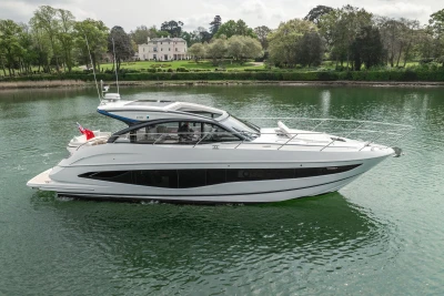 2025 Princess V50 yacht cruising on a serene river with lush greenery in the background.