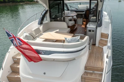 Luxurious 2025 Princess V50 yacht with elegant deck and seating area, featuring a red flag.