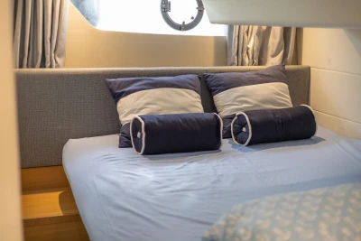 Cozy cabin bed in 2015 Princess V39 yacht with blue and white pillows.
