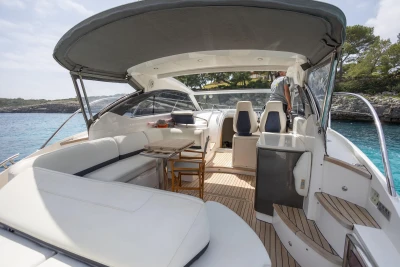 Luxurious 2015 Princess V39 yacht interior with seating, table, and helm, docked by clear waters.