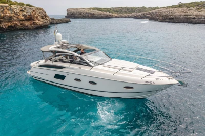 Luxury 2015 Princess V39 yacht cruising in clear blue waters near rocky cliffs.