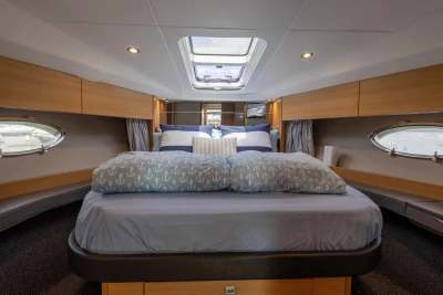 Luxurious cabin interior of 2015 Princess V39 yacht with elegant bedding and porthole windows.
