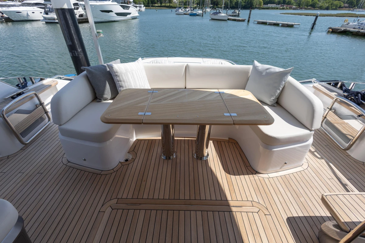 Luxurious seating area on 2025 Princess S65 yacht with wooden deck and scenic marina view.