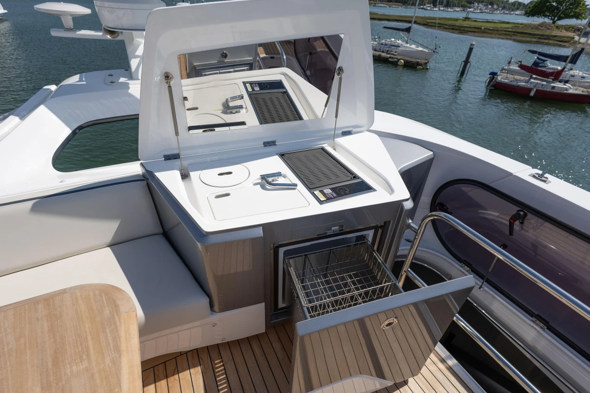 Outdoor kitchen on 2025 Princess S65 yacht with grill and storage, docked by the water.