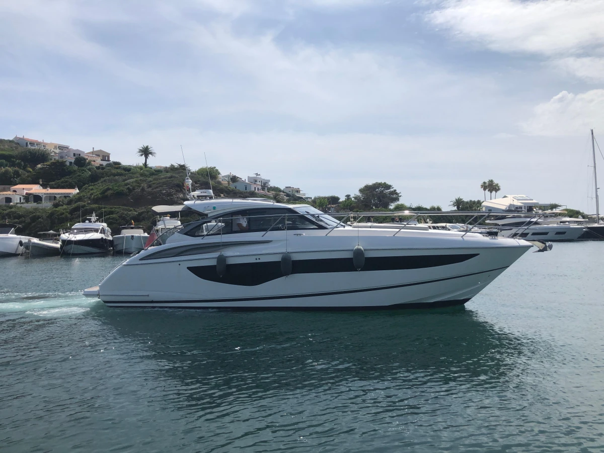 2022 Princess V40 yacht cruising in a scenic harbor with lush greenery.