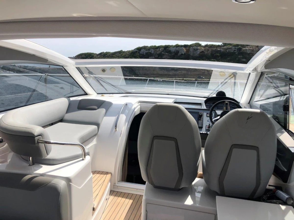 2022 Princess V40 yacht interior with modern seating and steering, overlooking scenic water view.