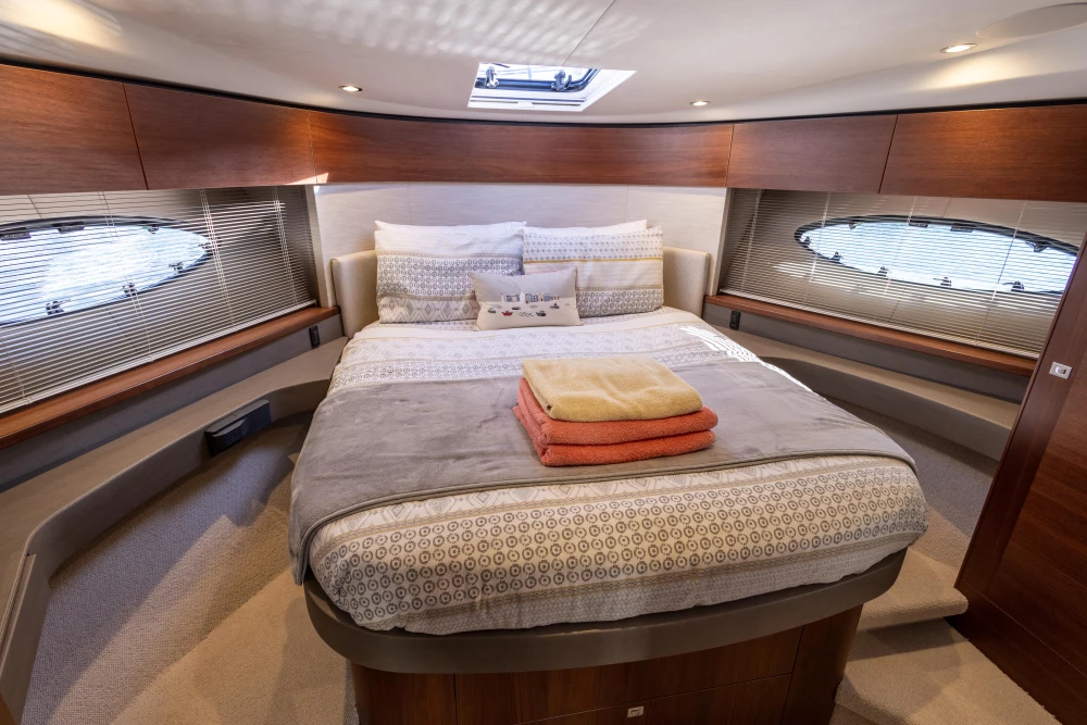 Luxurious cabin interior of 2018 Princess 43 yacht with cozy bed and elegant decor.