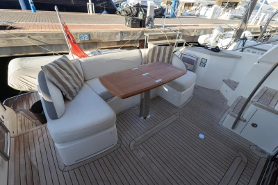 Luxurious 2018 Princess 43 yacht deck with seating and table, docked at marina.