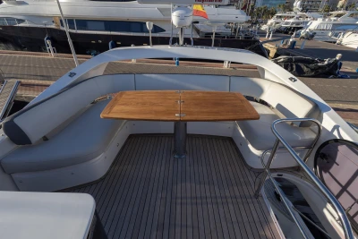 Luxurious 2018 Princess 43 yacht deck with seating and wooden table at marina.