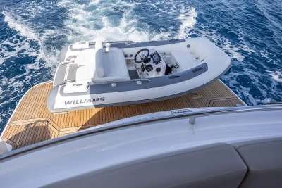 Luxury yacht Princess F65 with tender boat on teak deck, cruising through blue ocean waters.