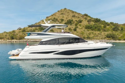 Luxurious 2025 Princess F65 yacht cruising in serene blue waters near a lush green island.