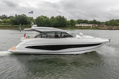 2023 Princess V50 yacht cruising on a serene river with lush greenery in the background.