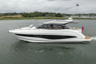 2023 Princess V50 yacht cruising on a calm river with scenic background.