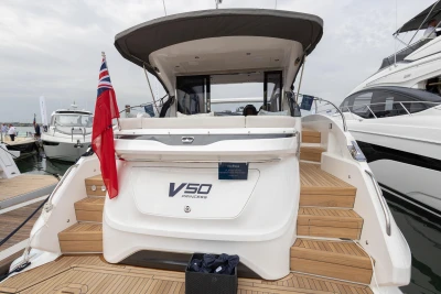 2023 Princess V50 yacht with wooden deck and red flag, docked at marina.