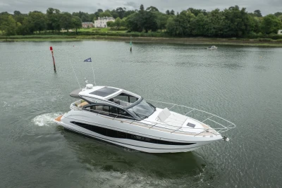 2023 Princess V50 yacht cruising on a calm river with lush greenery in the background.