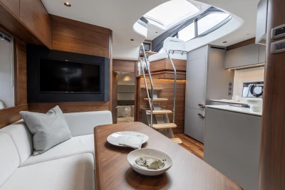 Luxurious 2023 Princess V50 yacht interior with modern kitchen, cozy seating, and elegant wood finishes.