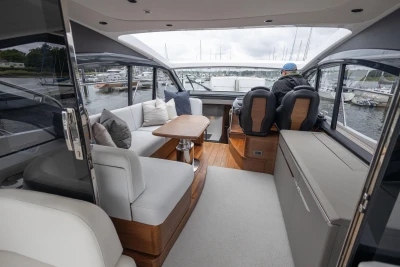 Luxurious 2023 Princess V50 yacht interior with seating and helm, docked at marina.