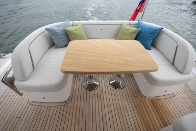 Luxurious seating area on 2023 Princess V50 yacht with cushions and wooden table.
