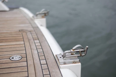 Teak deck of 2000 Princess V42 yacht with metal cleats by the water.