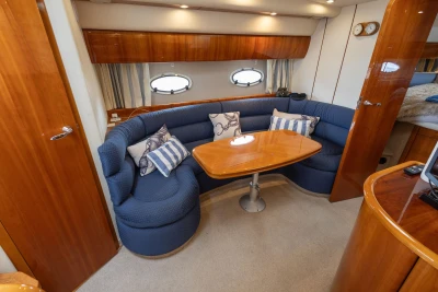 Luxurious interior of 2000 Princess V42 yacht with blue seating and wooden table.