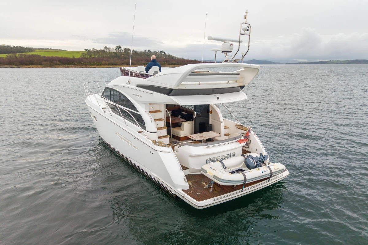 Luxury 2017 Princess 43 yacht on serene water, rear view with tender boat.