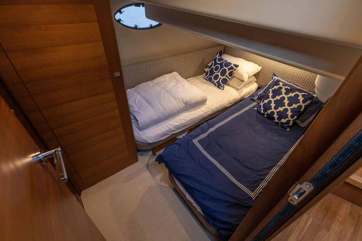 Cozy cabin interior of 2017 Princess 43 yacht with twin beds and nautical decor.