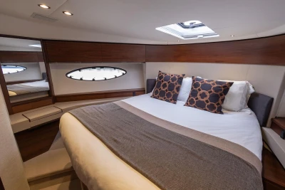 Luxurious cabin interior of 2018 Princess 49 yacht with elegant bedding and wood accents.