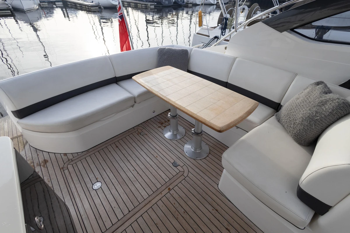Luxurious seating area on 2013 Princess V39 yacht with wooden table and plush cushions.