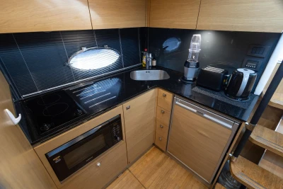 Modern kitchen in a 2013 Princess V39 yacht with appliances and sleek black countertops.