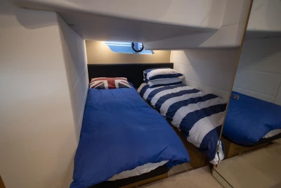Twin cabin beds in 2013 Princess V39 yacht, featuring nautical-themed bedding.