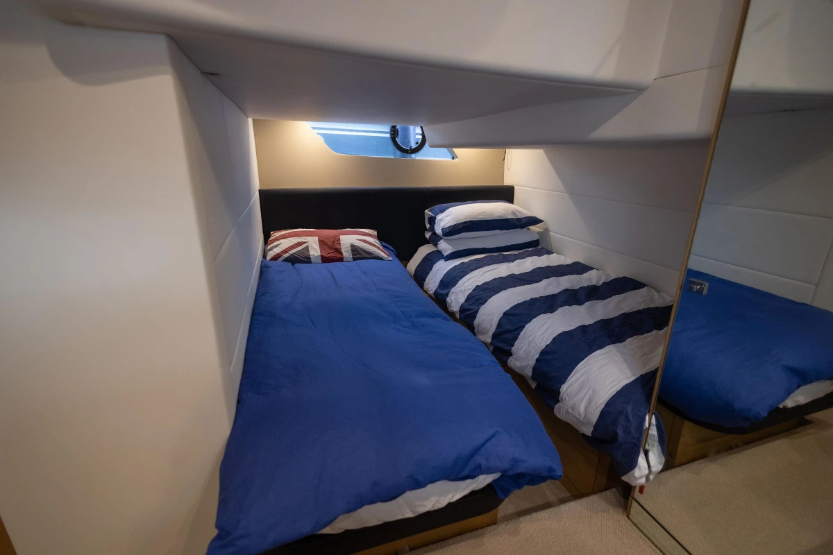 Twin cabin beds in 2013 Princess V39 yacht, featuring nautical-themed bedding.