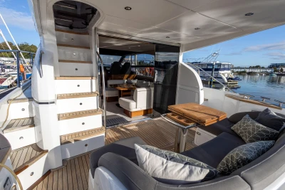 Luxurious 2016 Princess 43 yacht interior with seating, table, and stairs, docked at marina.
