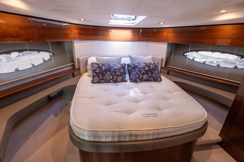 Luxurious cabin interior of 2016 Princess 43 yacht with plush bedding and elegant wood finishes.