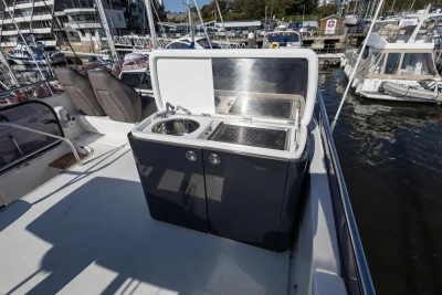 Outdoor kitchenette on 2016 Princess 43 yacht, featuring sink and grill, docked at marina.