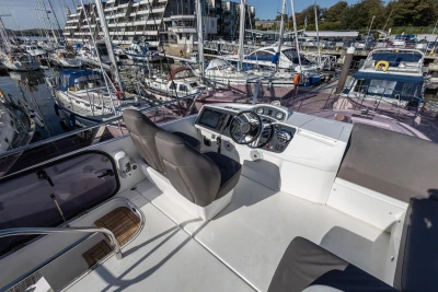 Flybridge of 2016 Princess 43 yacht in marina, featuring helm and seating area.