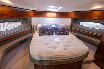 Luxurious cabin interior of 2016 Princess 43 yacht with plush bedding and elegant wood finishes.
