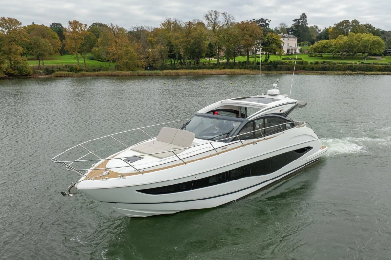 2022 Princess V50 yacht cruising on a serene river with lush greenery in the background.