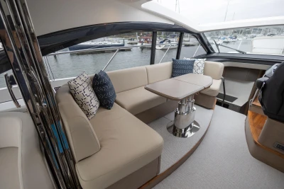 Luxurious 2022 Princess V50 yacht interior with elegant seating and table, docked at marina.